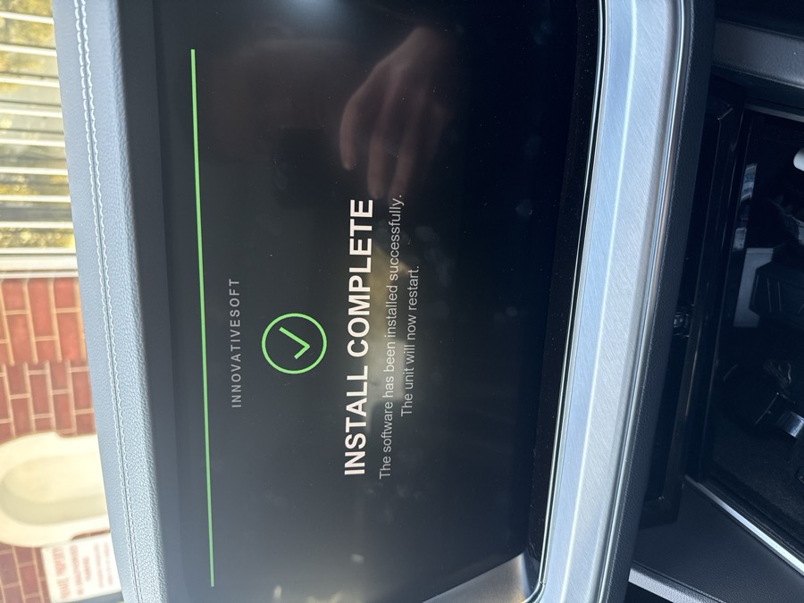 Car screen with a green tick reading Install Complete, the software has been installed successfully, the unit will now restart